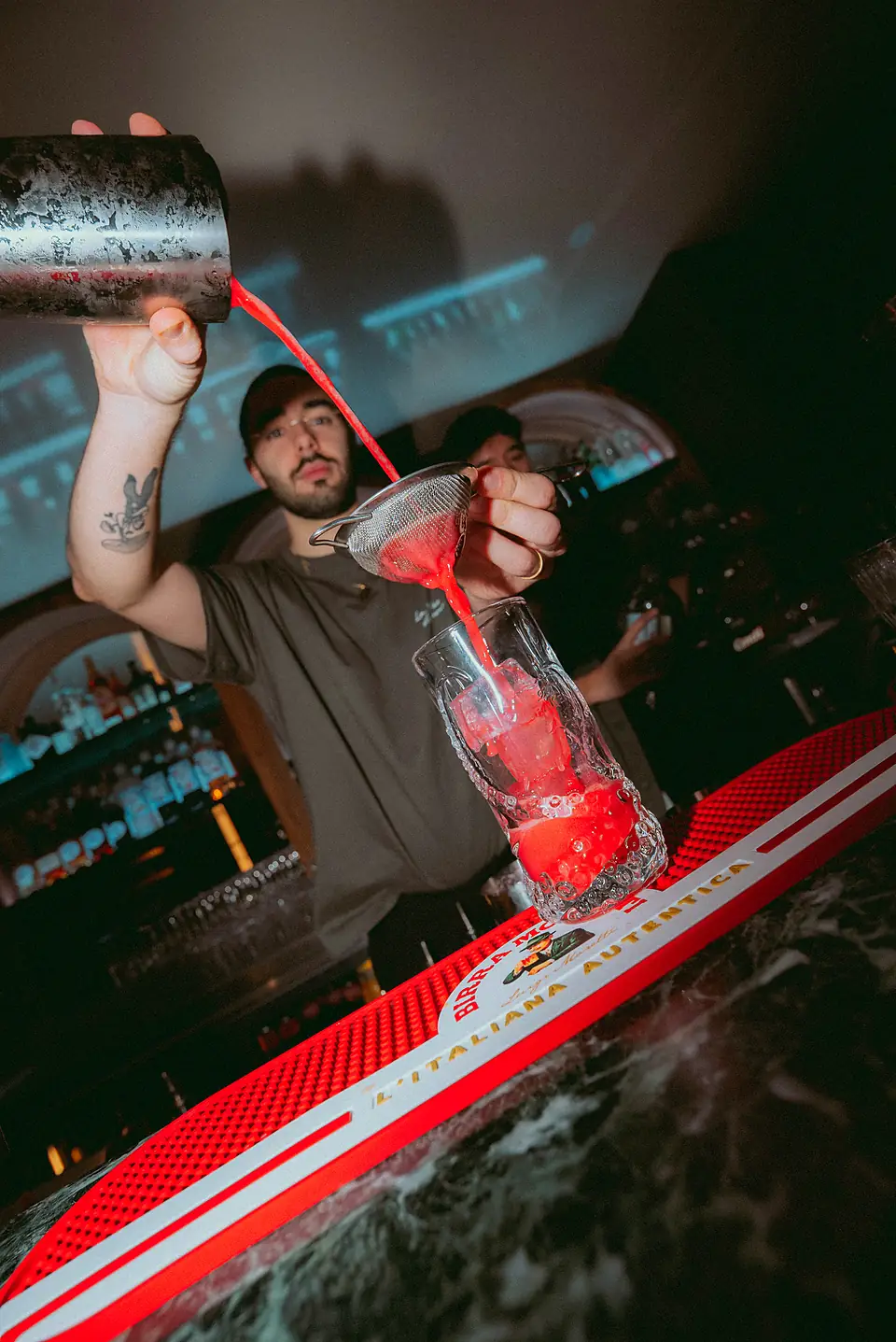 Le barman verse un cocktail rouge
